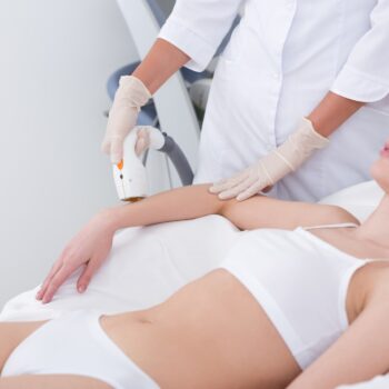 cropped shot of woman getting laser hair removal procedure on arm in salon