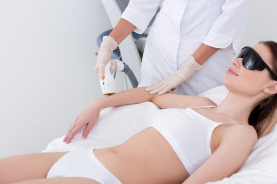 cropped shot of woman getting laser hair removal procedure on arm in salon