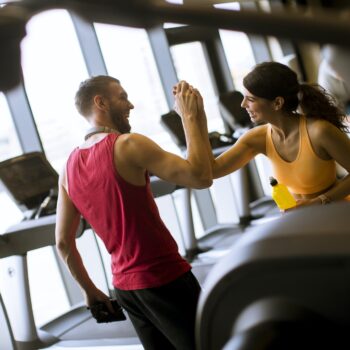 Young woman and personal trainer rest in the gym after workout