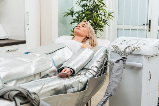 Blonde girl lying with closed eyes during pressotherapy session in clinic