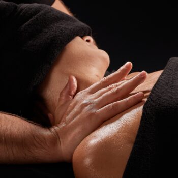 a male masseur massages a girl's neck on a dark background, neck massage