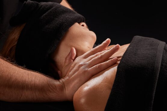 a male masseur massages a girl's neck on a dark background, neck massage